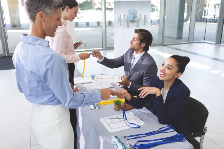 Side view of diverse business people checking in at conference registration table in office lobby